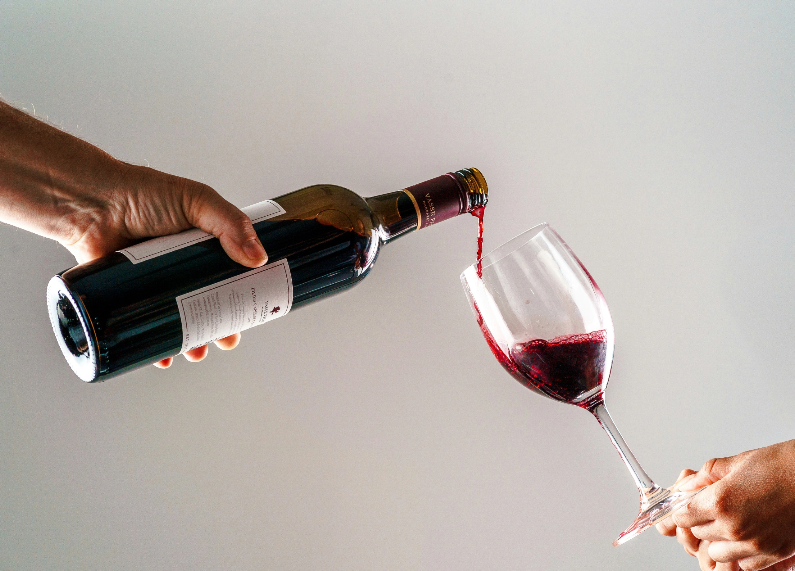 red wine being poured in glass from bottle